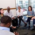 A group of people sit in a circle an laugh together during a group therapy session.