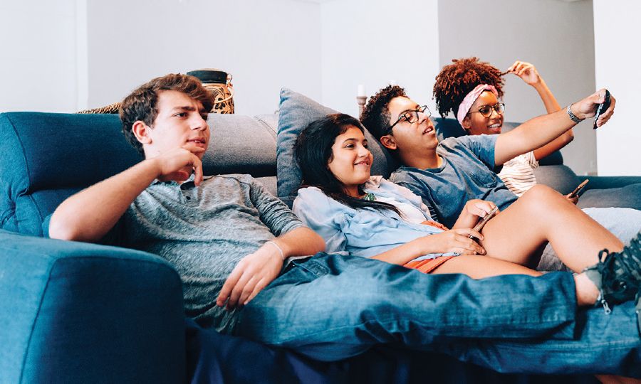 Group of teenagers on a couch, channel-surfing