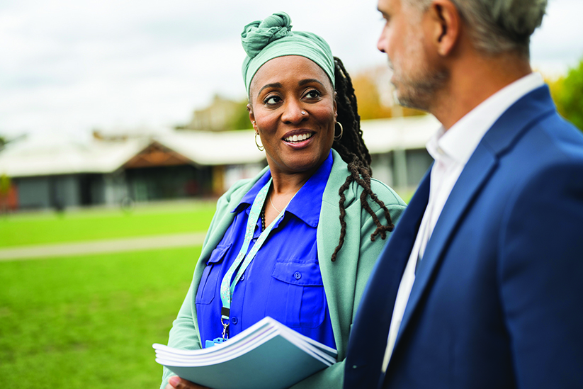 Cheerful female teacher talking with male colleague outdoors